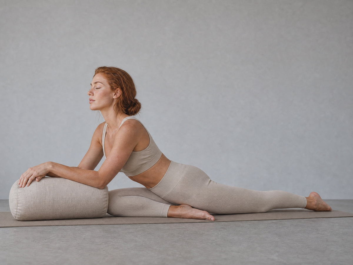 A yin practitioner resting forward over a bolster in a supported half-split