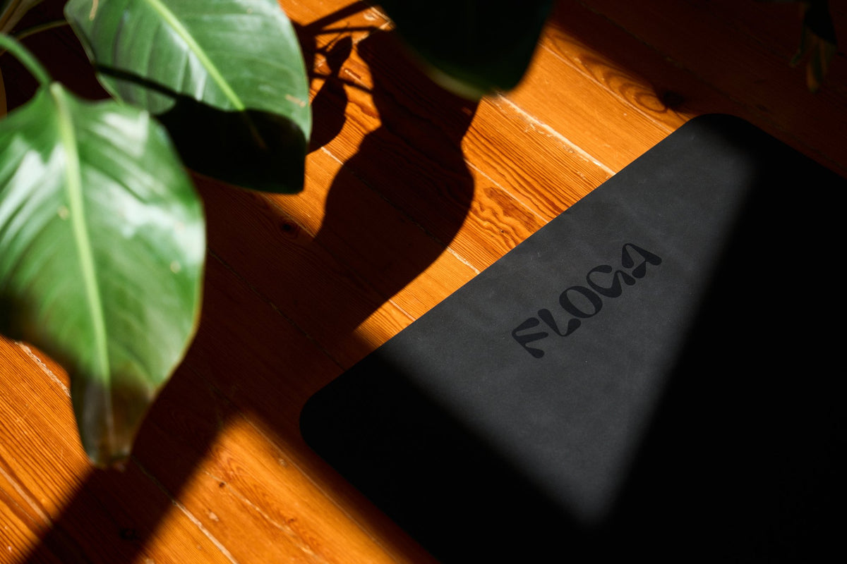 The Floga Mat on a wooden floor in sunlight, logo on its textured surface