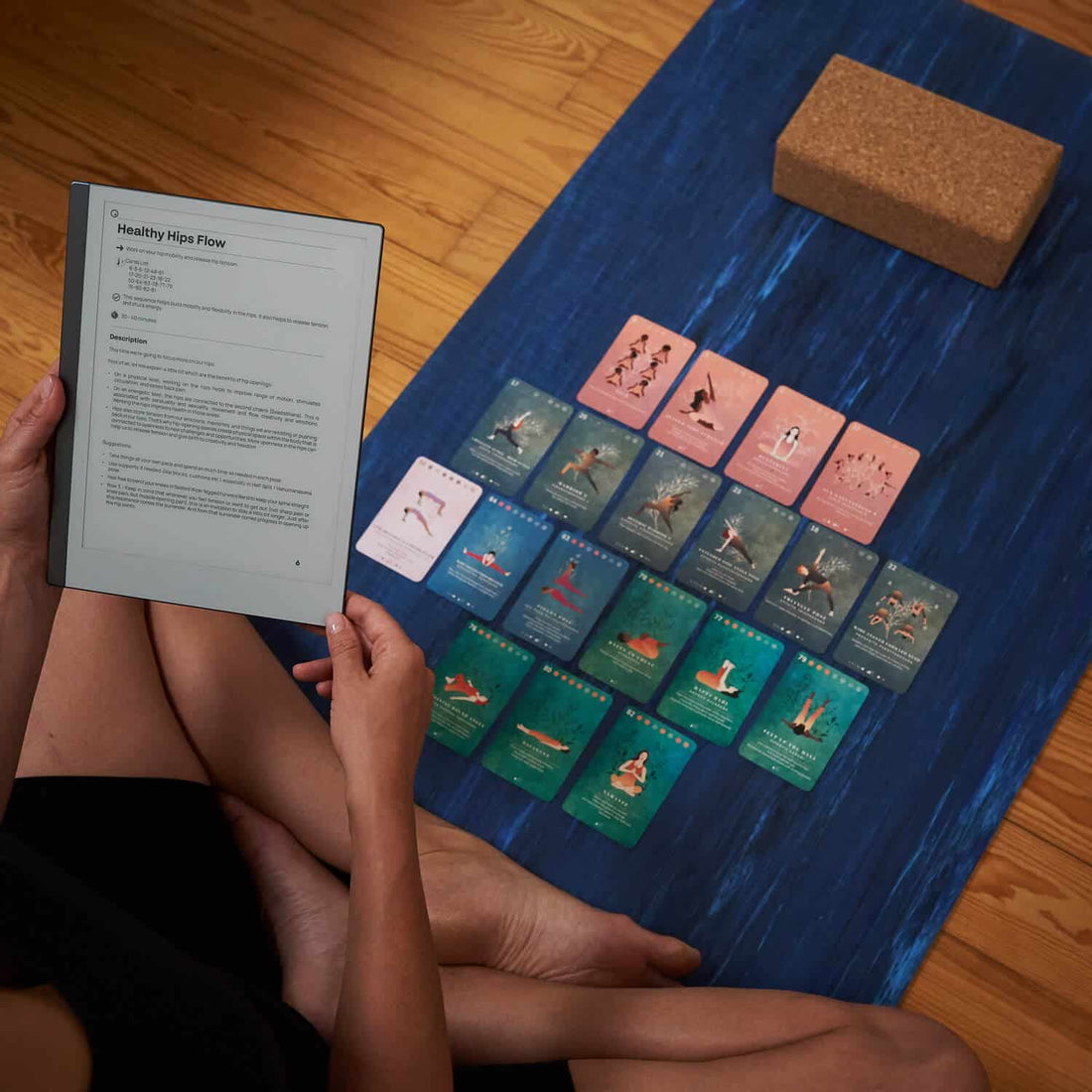 Reading a sequence from the guidebook beside the cards laid out on a yoga mat