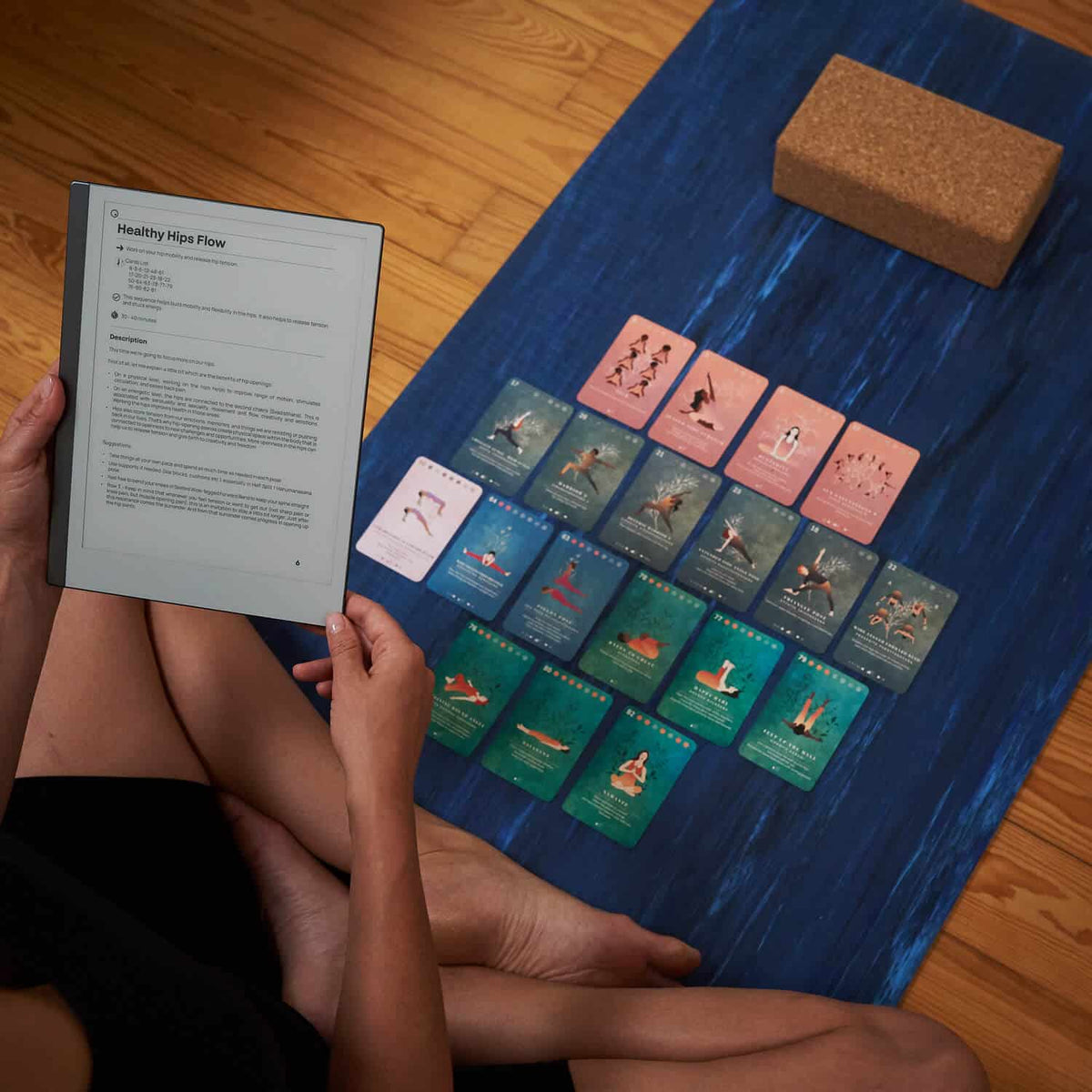 Reading a sequence from the guidebook beside the cards laid out on a yoga mat