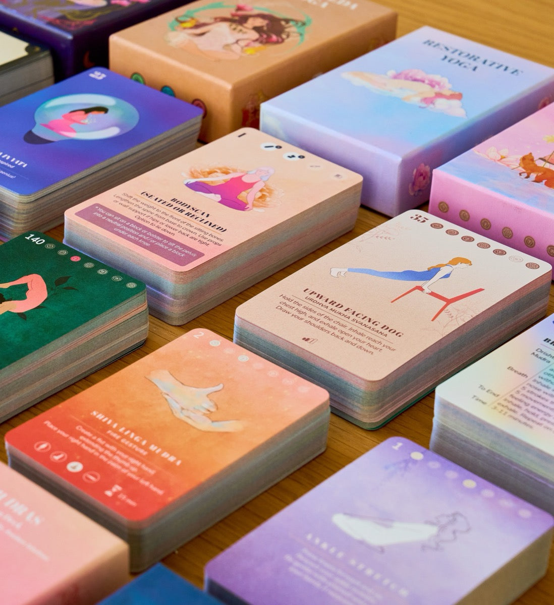 Cards and boxes from every PlayPauseBe deck laid out together on a wooden table
