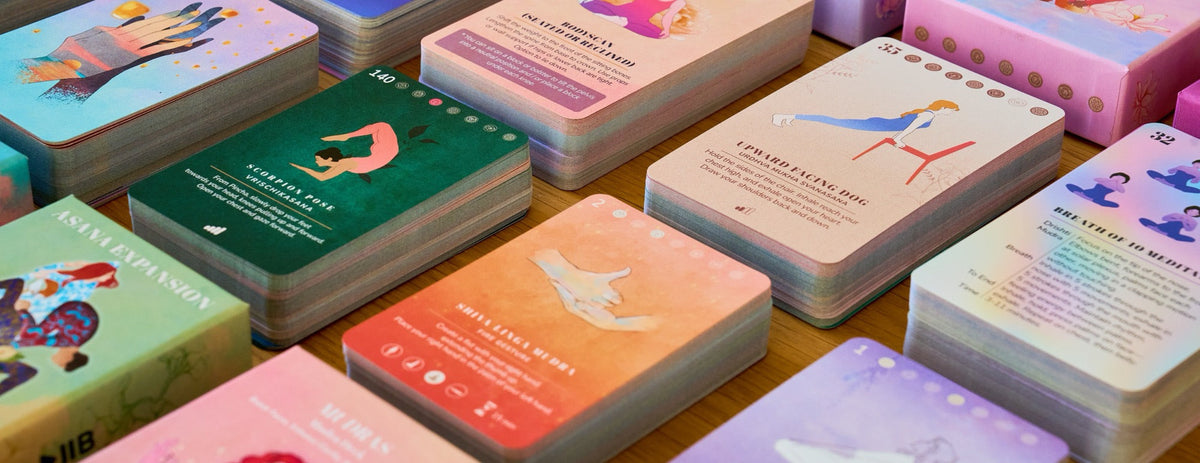 Cards and boxes from every PlayPauseBe deck laid out together on a wooden table