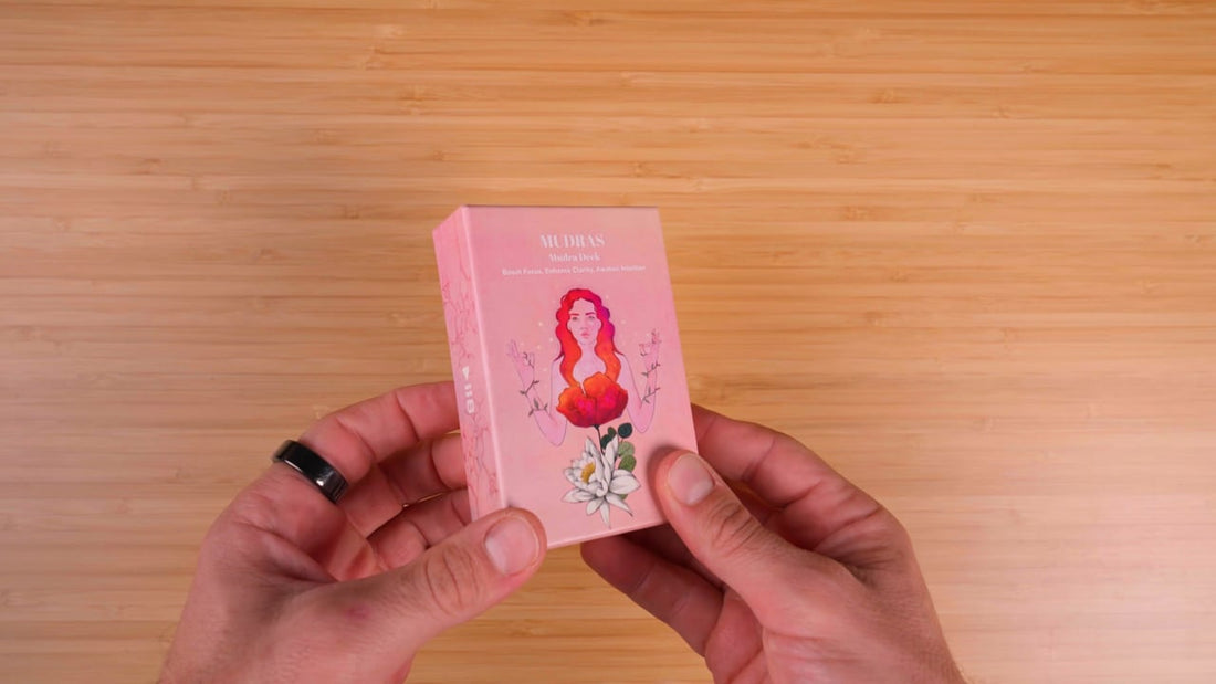 Hands holding the Mudra Deck box on a wooden table