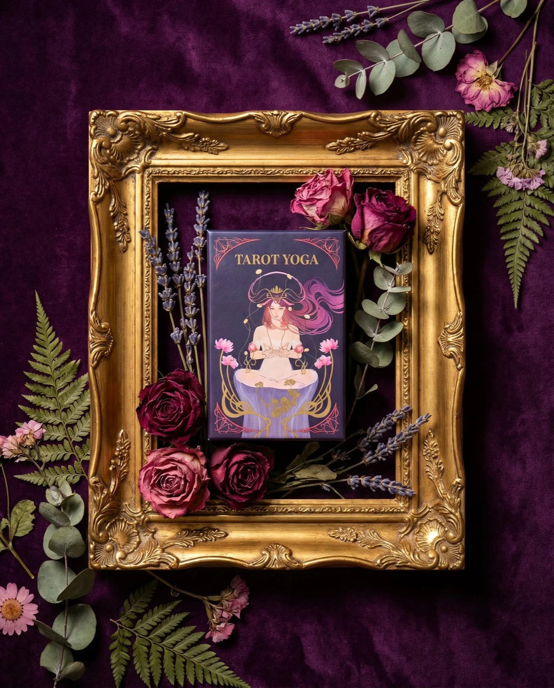 The Tarot Yoga Deck box in a gilded frame on plum velvet with dried roses