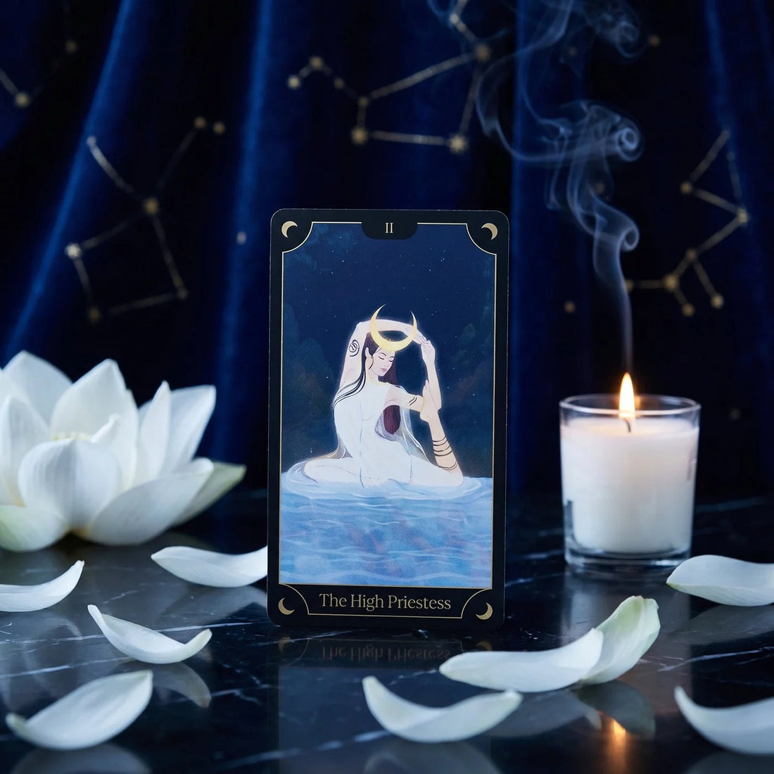 The High Priestess card on a candlelit altar with lotus petals